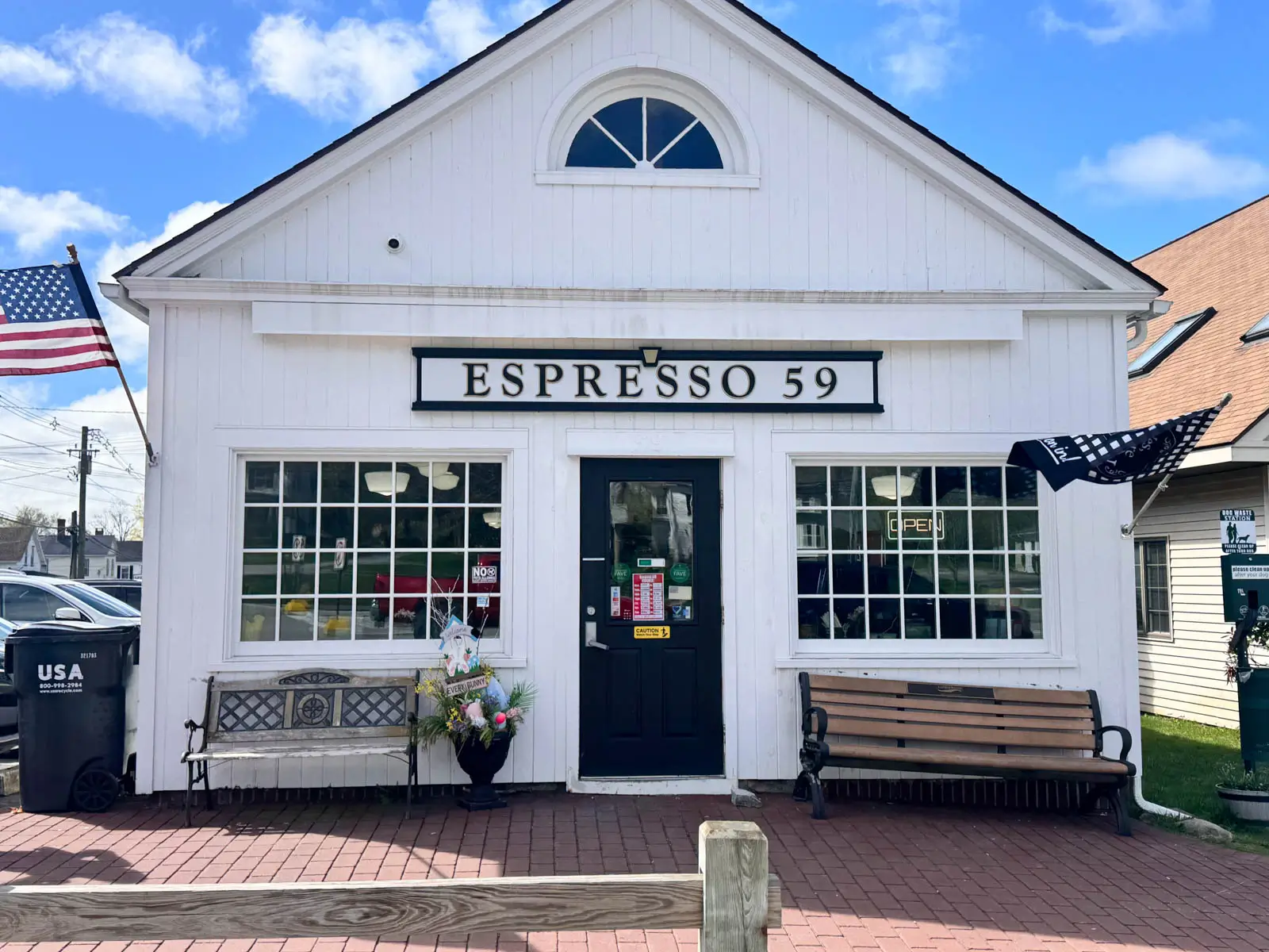 outside of small white coffee shop called espresso 59 in downtown litchfield with blue sky in background.