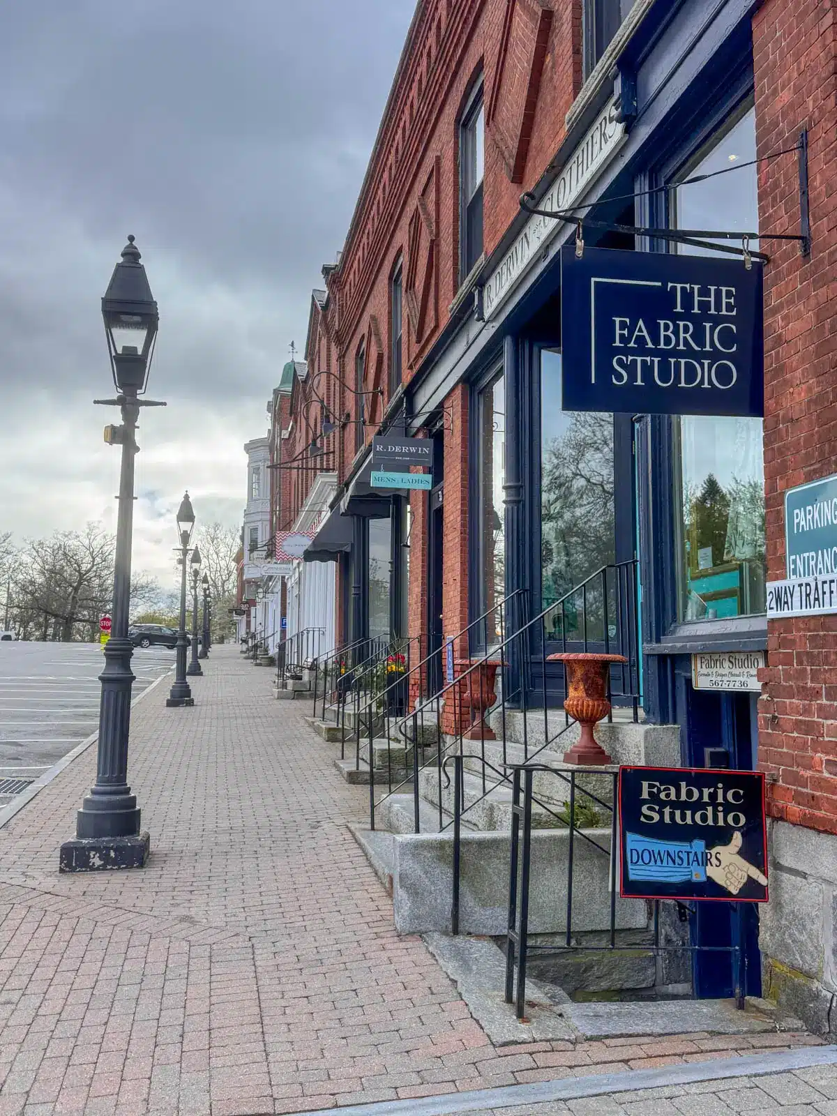 strip of west street in downtown litchfield with brick buildings and storefronts lining the stone walkway and lampposts along the path.