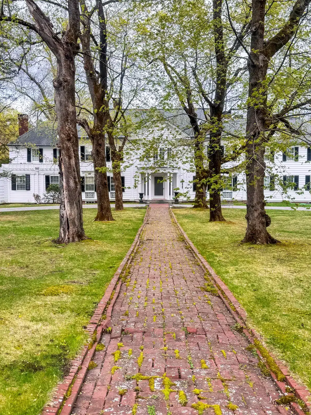 brick walkway leading to huge old white colonial home in historic litchfield with green grass.