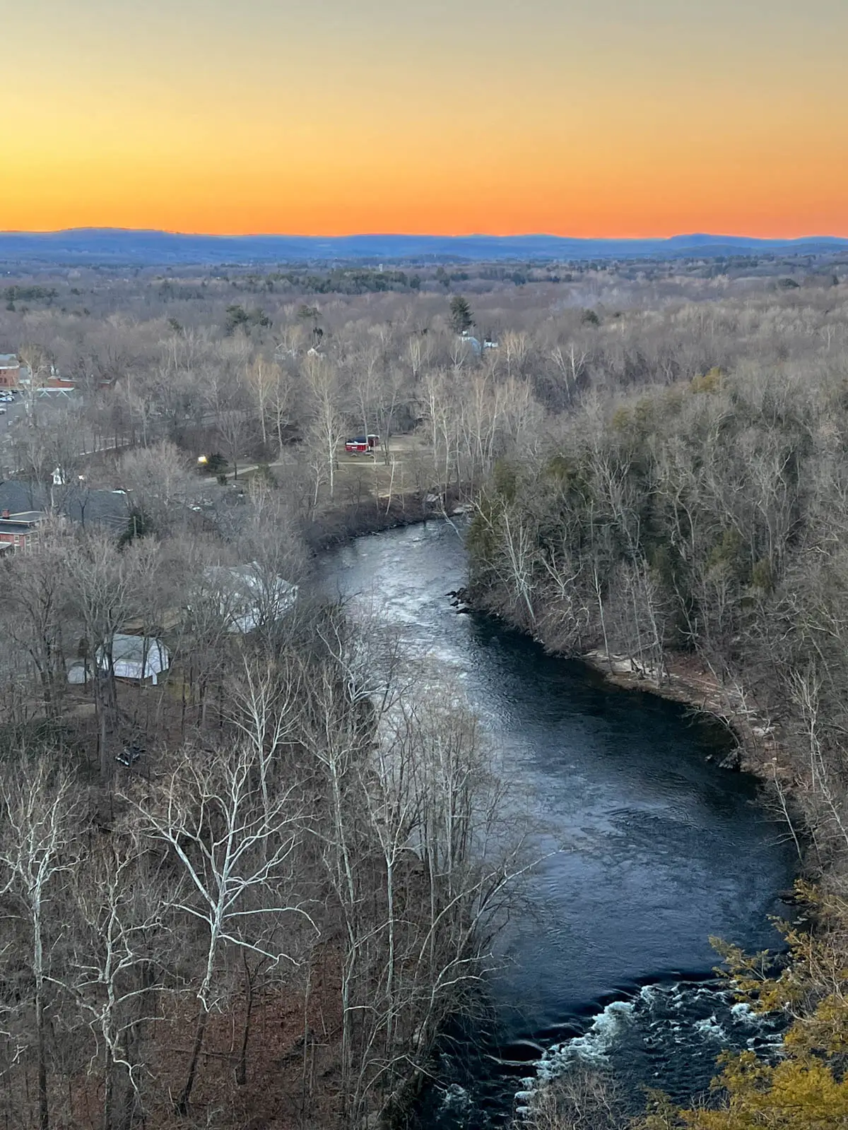 cliff view of farmington river below and glow of orange sunset sky.
