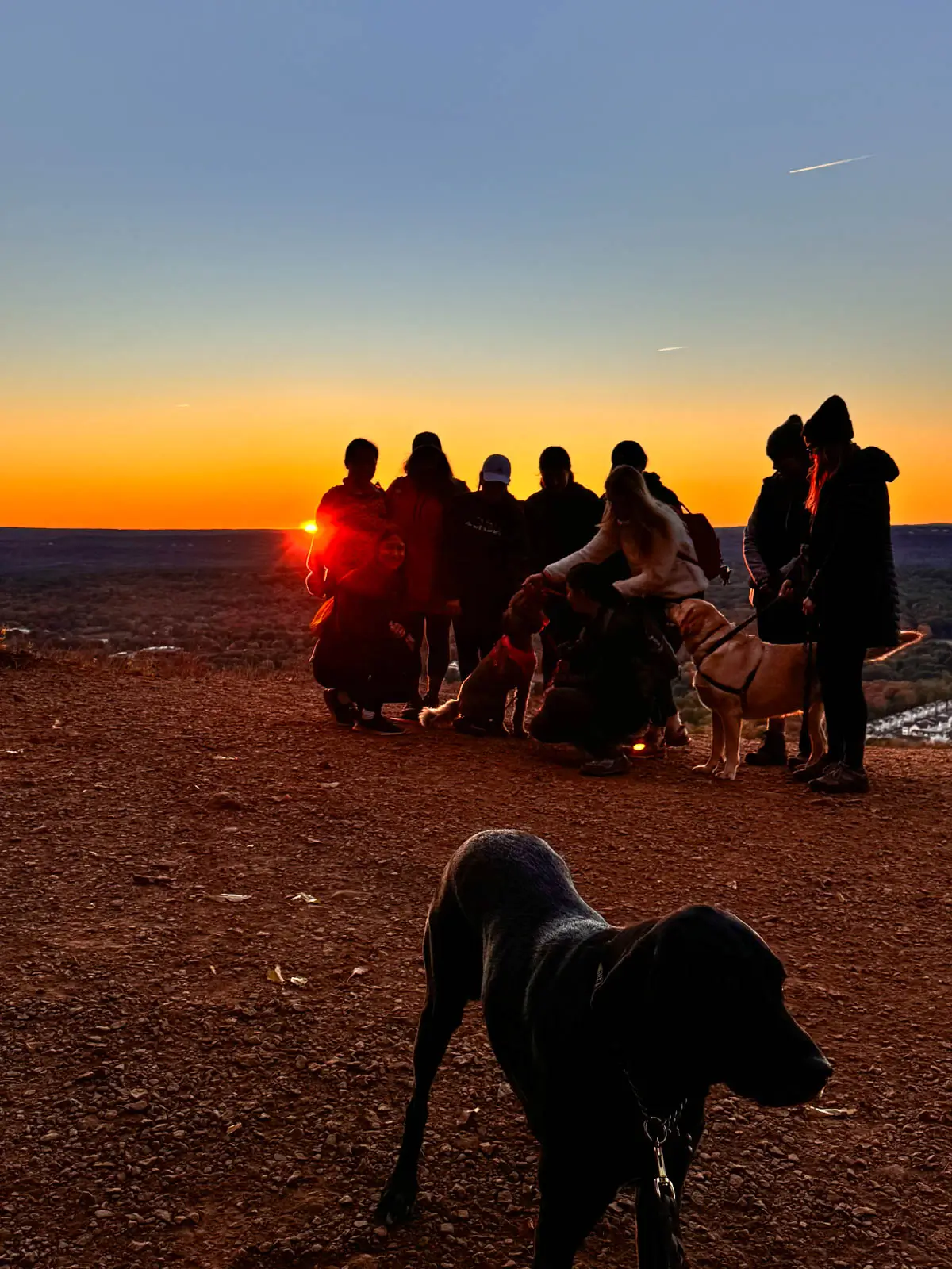 silhouette of groups of hikers at sunset with sun setting behind them.