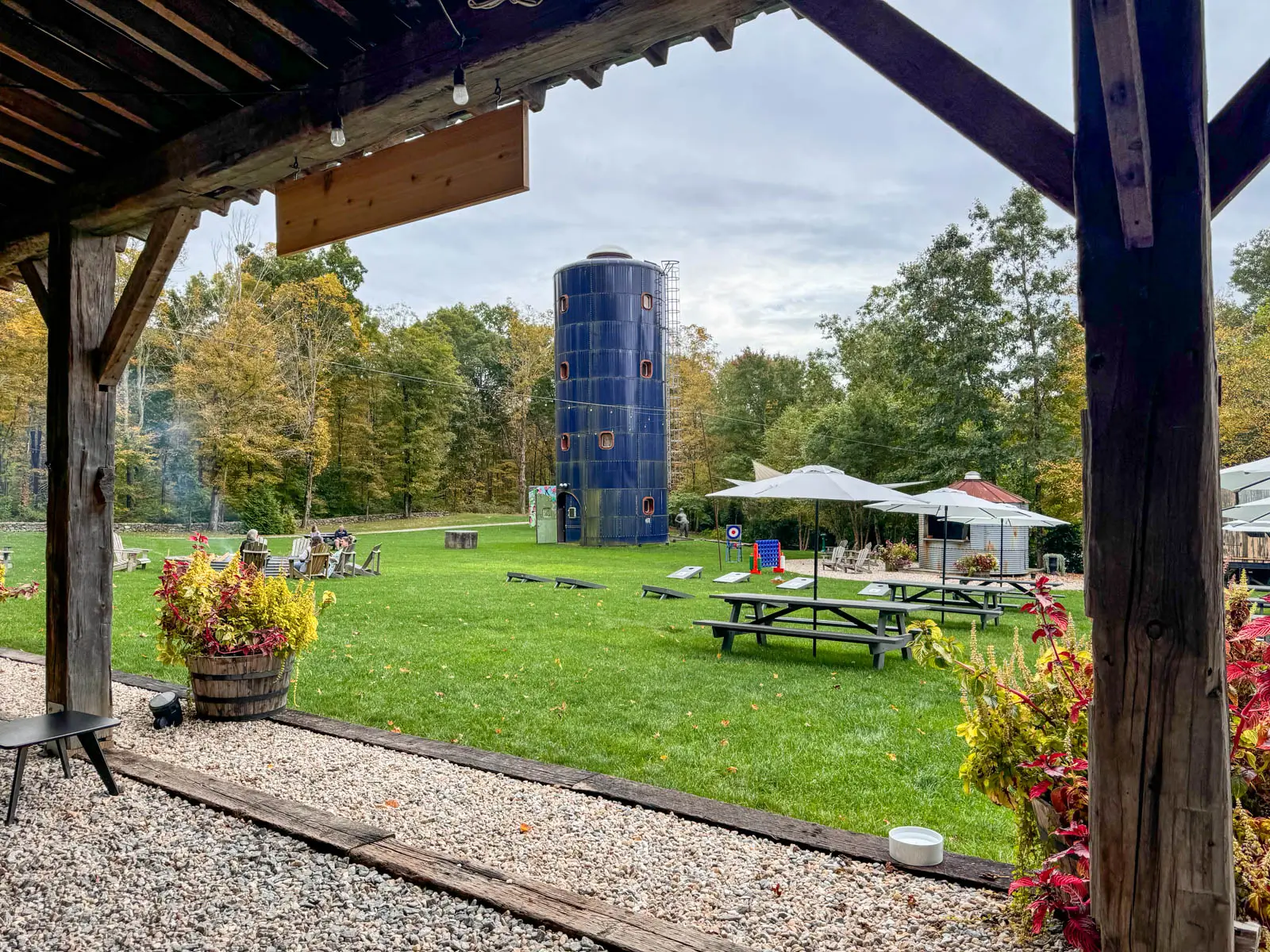 view of spring hill vineyard with picnic tables and umbrellas and fire put and fall colored trees lining the property.