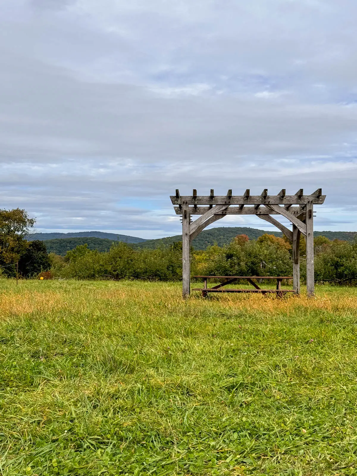 view from averill farm in washington connecticut in early fall with green field and rolling green and yellow hills in the distance.