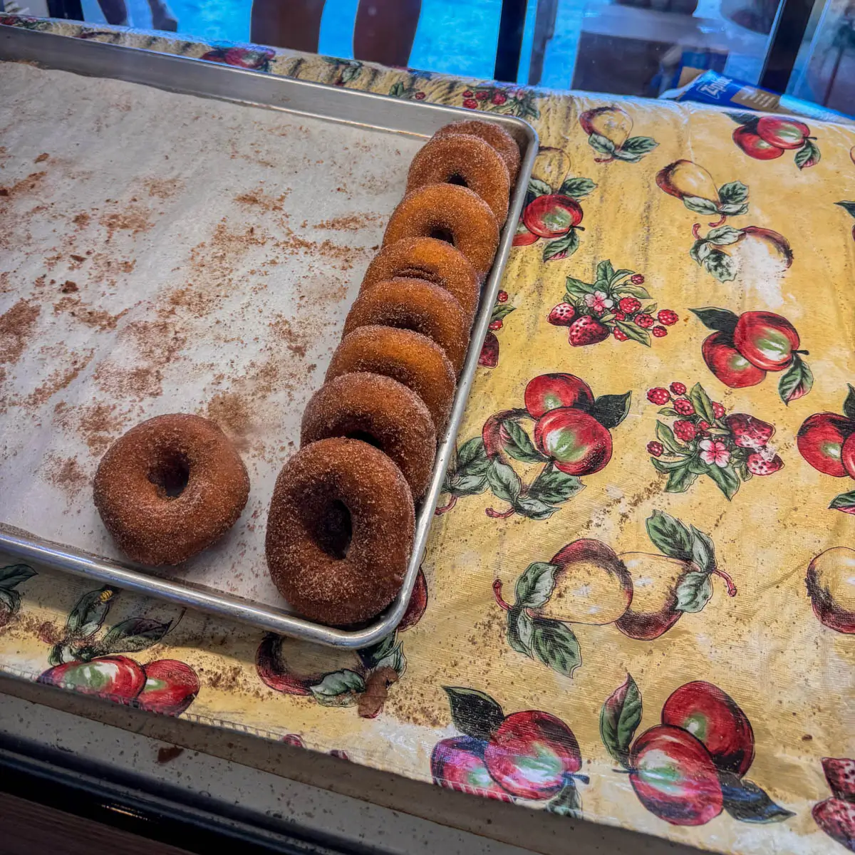 apple cider donuts in a row on a baking sheet.
