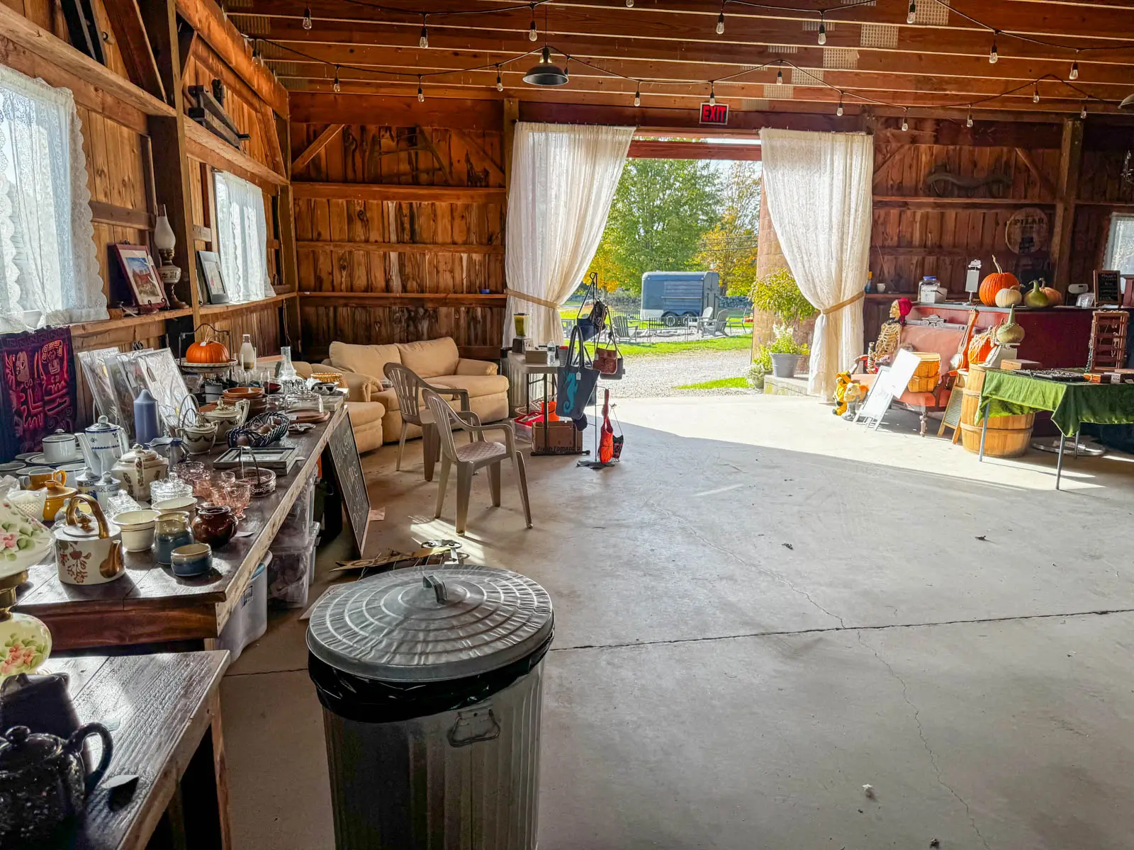 inside a big barn at bunnell farm in litchfield connecticut with tables set up with little antiques on the tables.