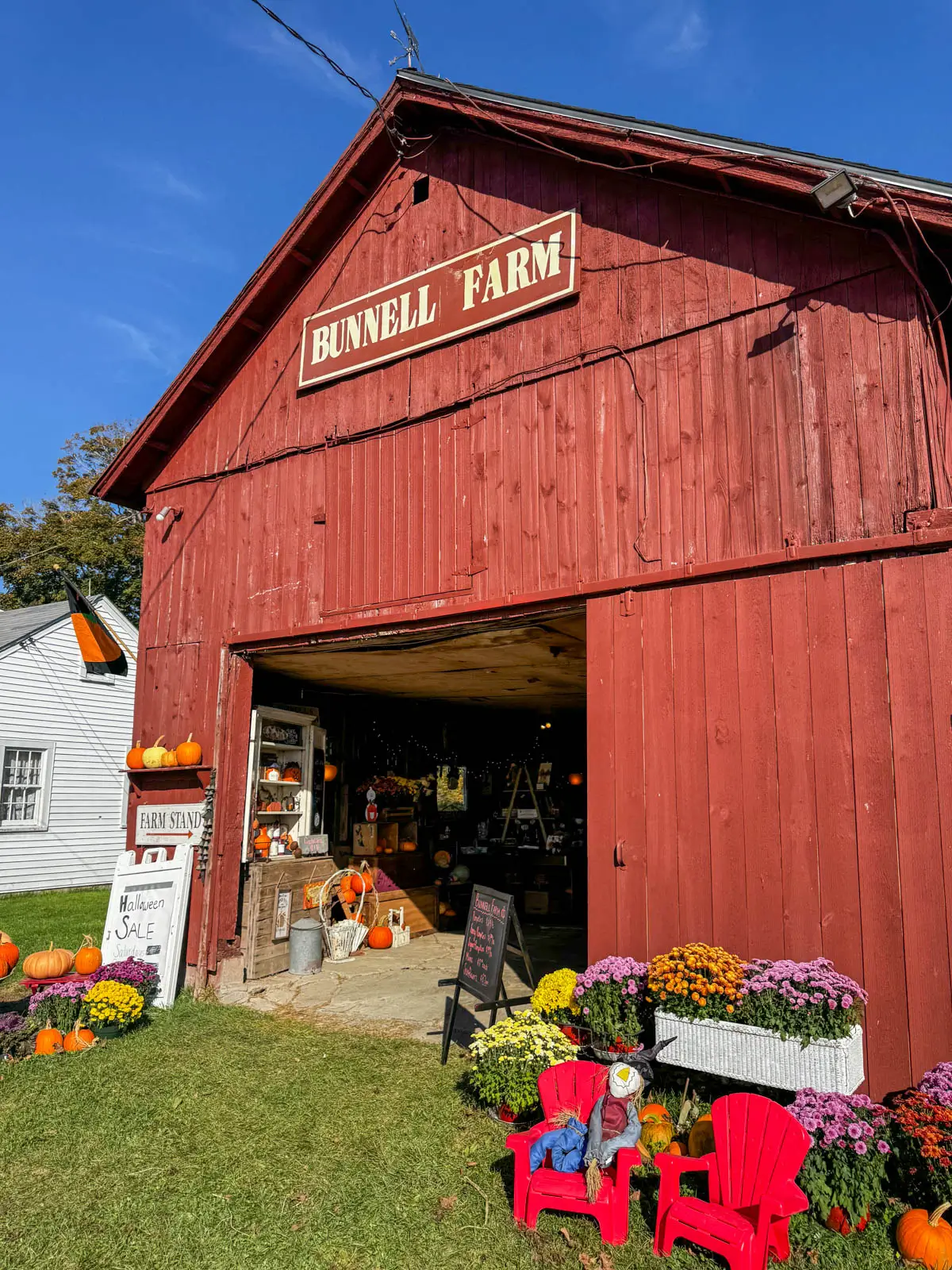 big red barn in litchfield connecticut with bunnell farm sign at the top and blue sky in background.
