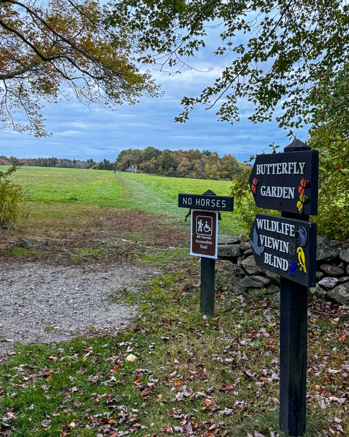 "butterfly garden' sign at topsmead state forest in litchfield in fall with yellow and green trees lining the trail in fall.