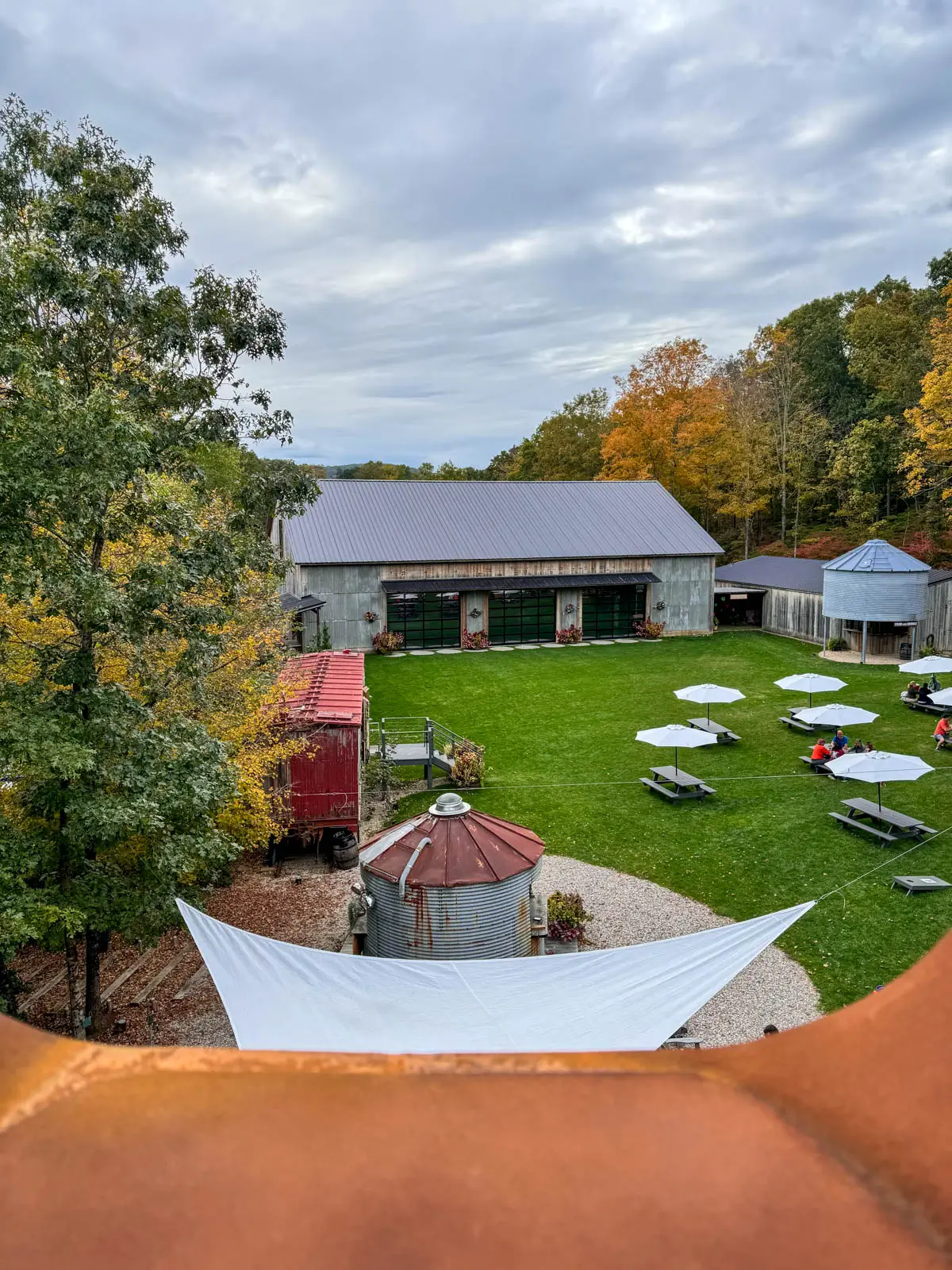 view from top of tower at spring hill vineyards in litchfield county with picnic tables sprinkled over green lawn and yellow trees lining the property.