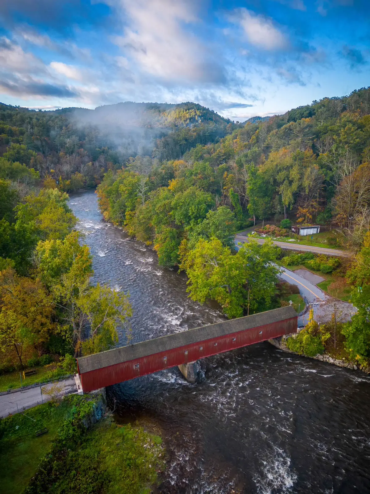 drone photo of long red covered bridge in cornwall connecticut in early fall.