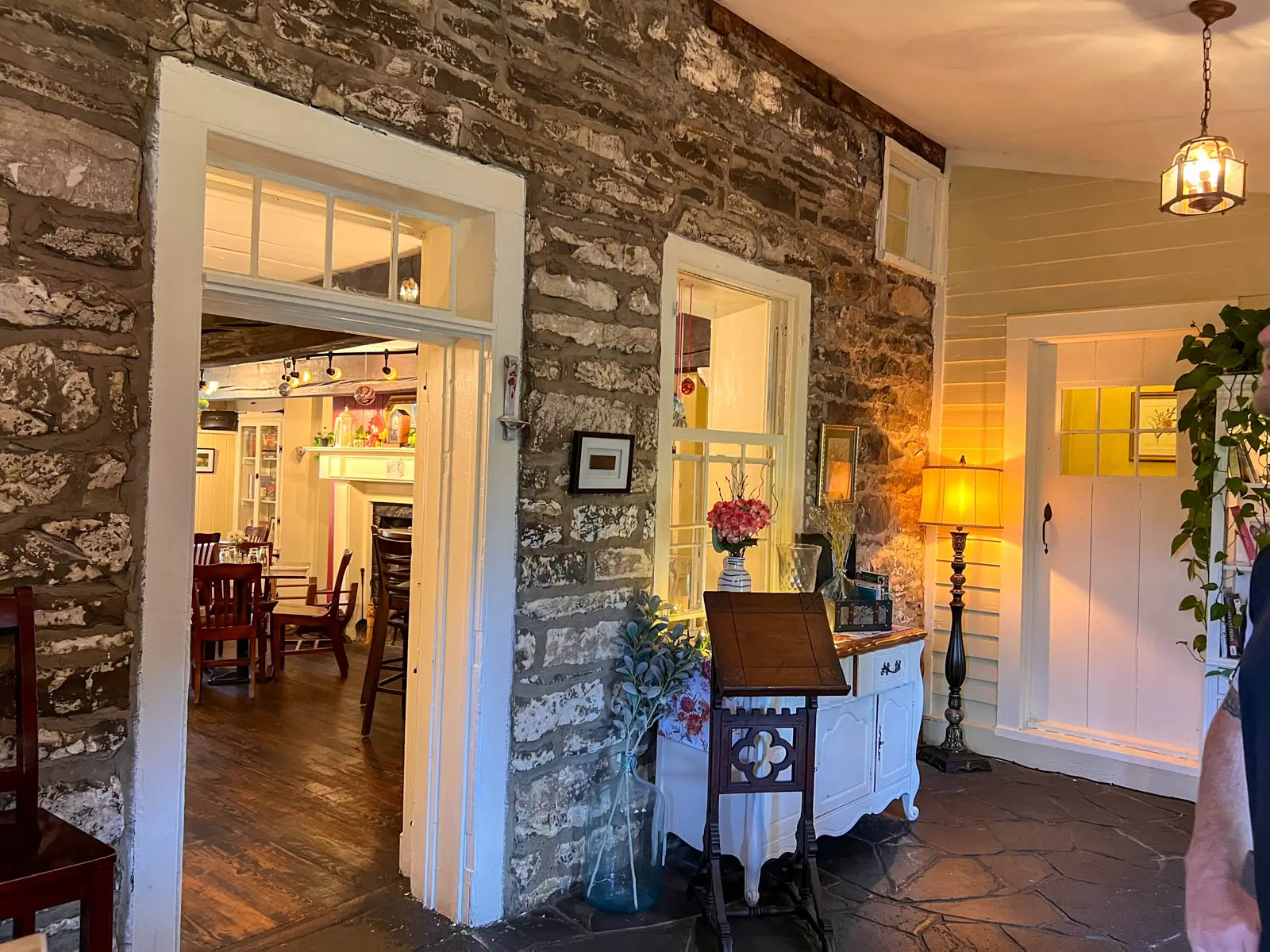 entryway inside of pub with stone wall and white door and door frames with soft lighting.