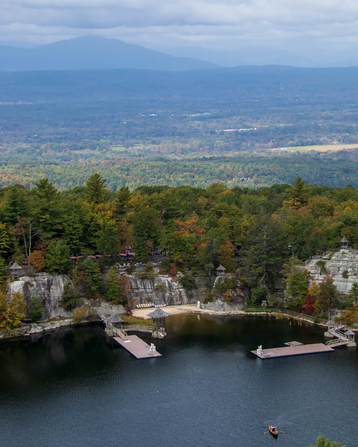 view from a hike looking over a big lake and green and gold leaves and trees at mohonk preserve in new york.