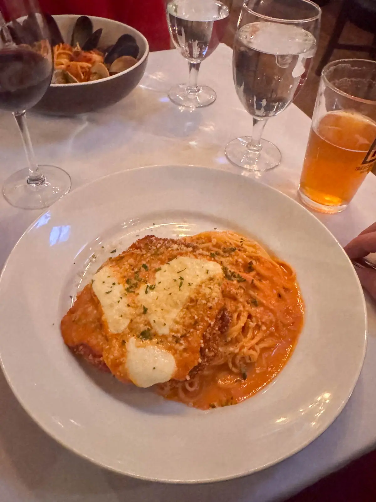 white plate with spaghetti and chicken parm on top.