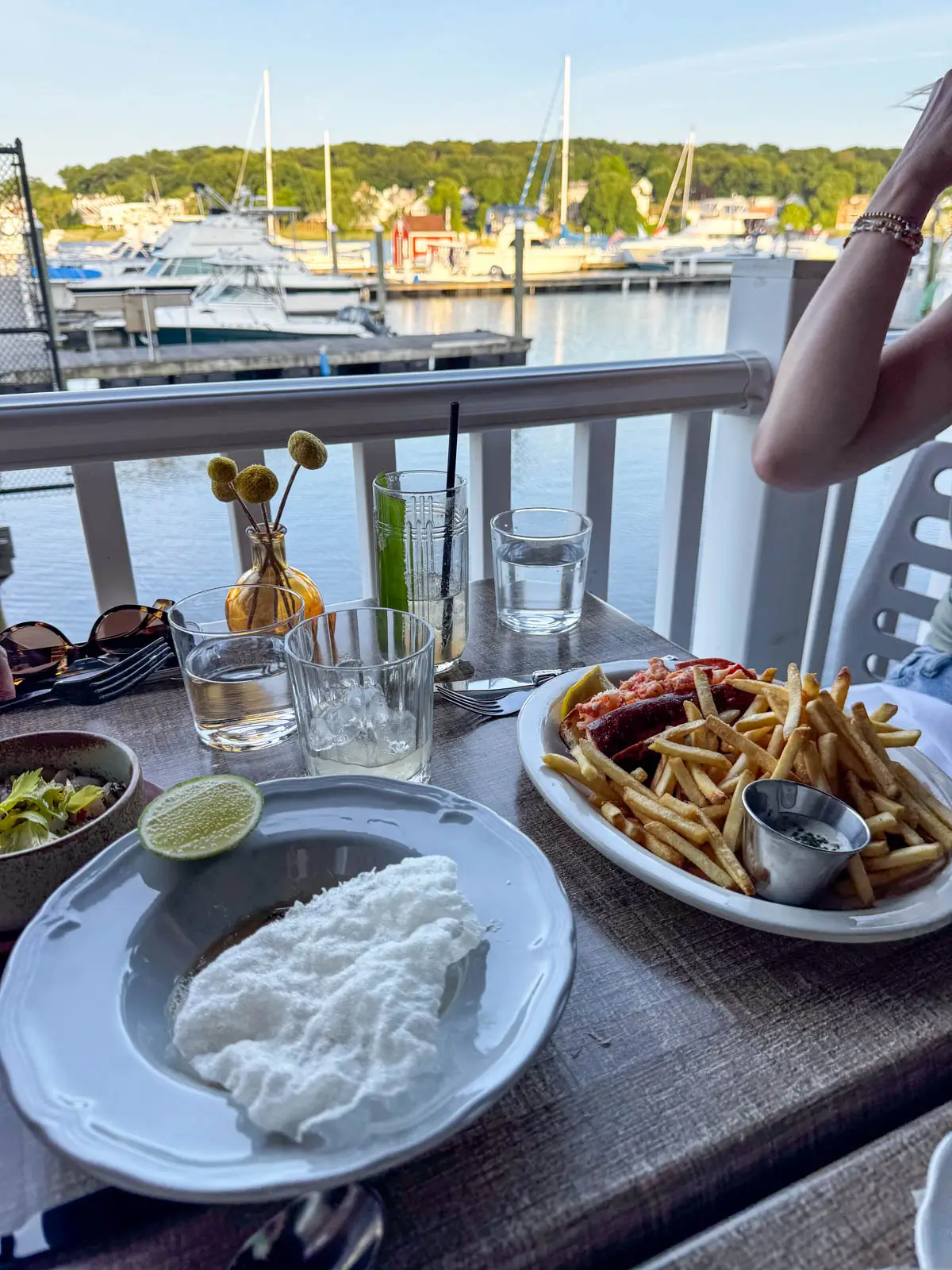 view of two white plates with food one of them has a burger of french fries and the other has a lemon wedge and a white rice cake.