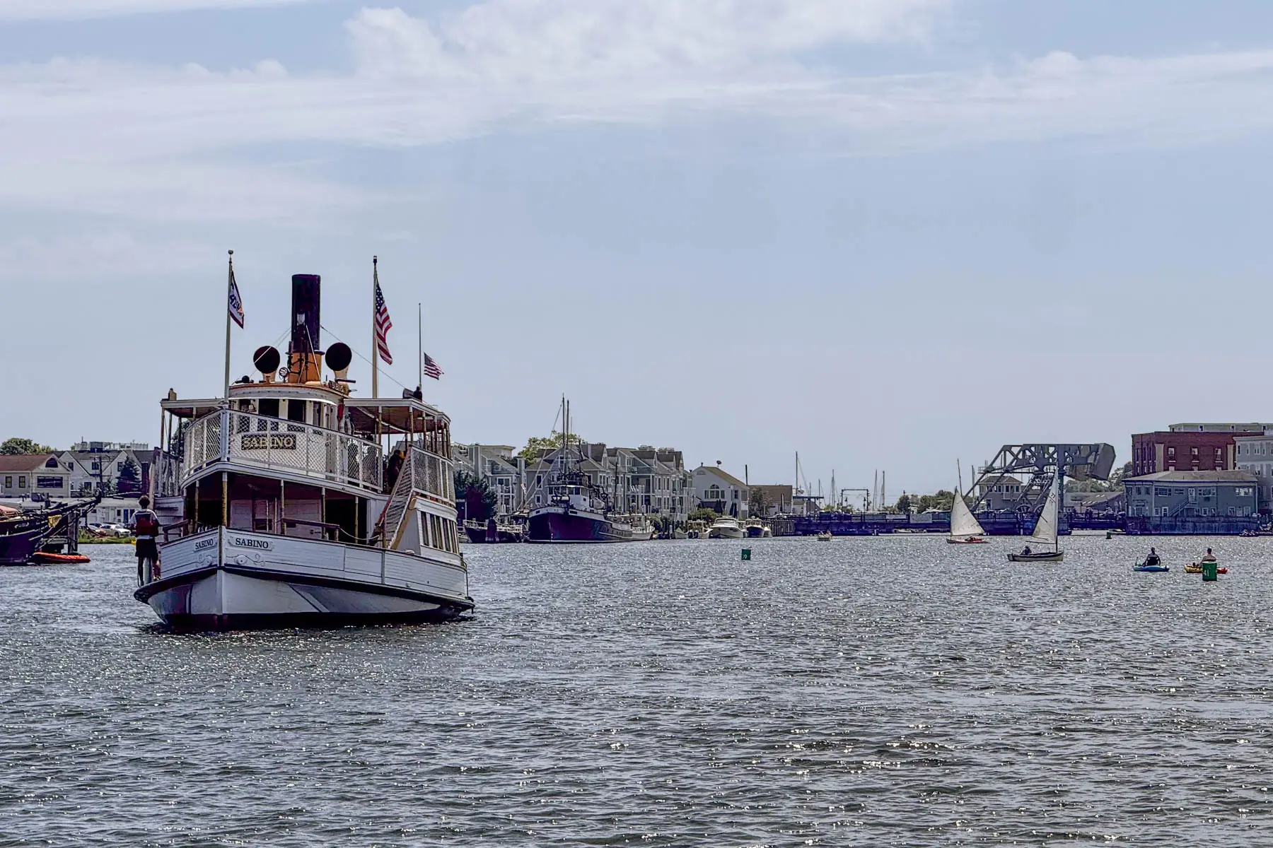 white tug boat on the water in mystic with hazy summer sky above.
