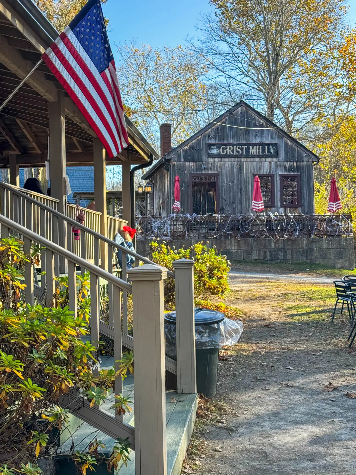 cider mill in mystic connecticut with small wooden clapboard gray building and stone wall in front.